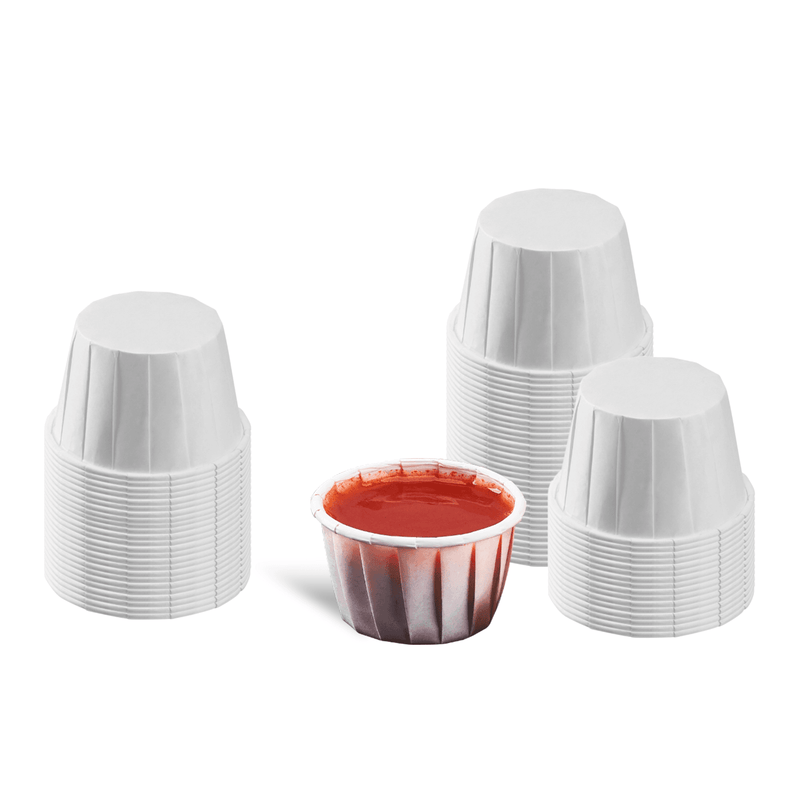Karat 1.25 oz Paper Portion Cups stacked and one with ketchup