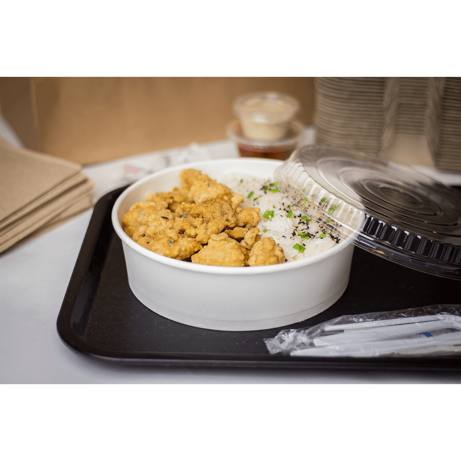 Karat 48oz Paper Short Buckets with chicken, rice, clear lid, and utensils on a serving tray