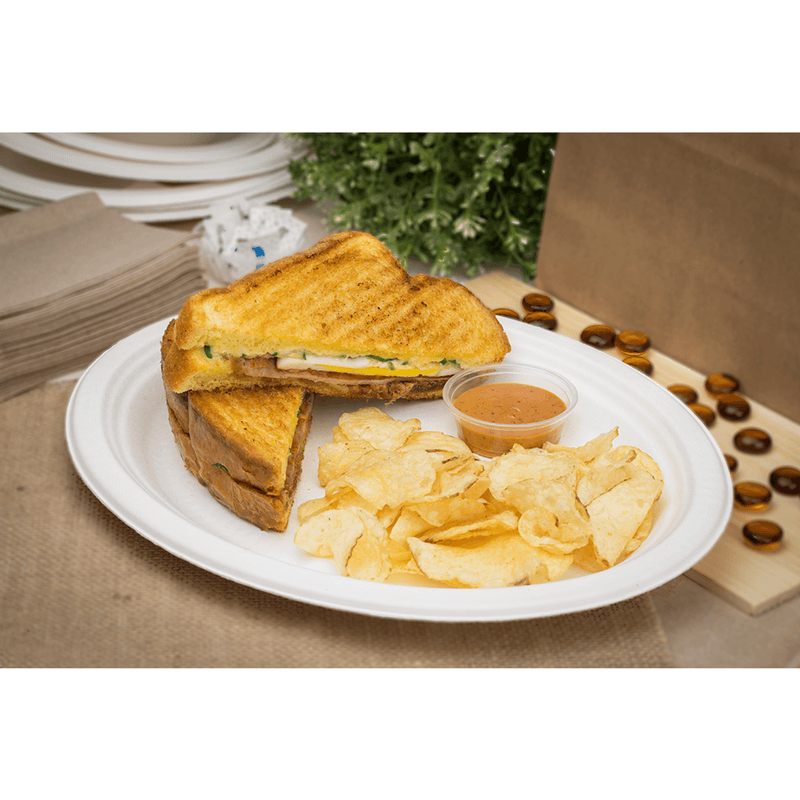 White Karat Earth 10''x8'' PFAS Free Compostable Bagasse Oval Plates with sandwich and chips
