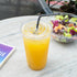 Clear Karat 107mm PET Plastic Flat Lids on cup with yellow drink