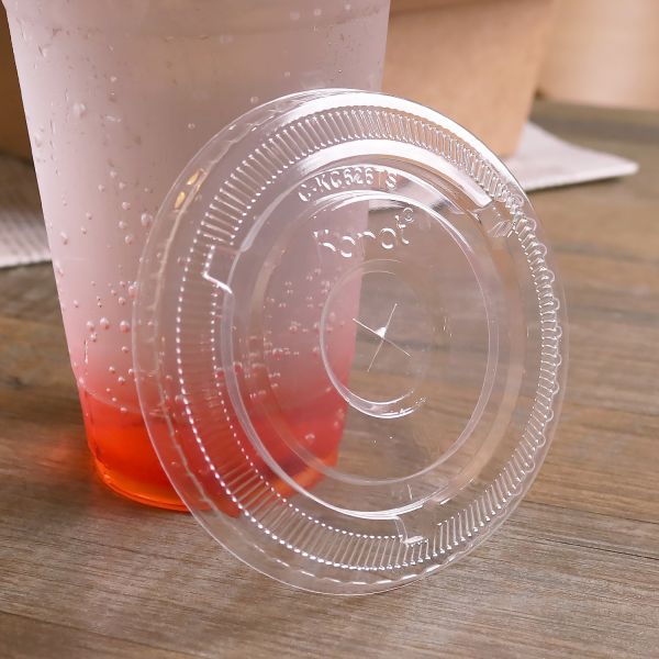 Clear Karat 98mm PET Plastic Flat Lids beside matching clear cup