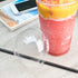 Clear Karat 107mm PET Plastic Dome Lid beside cup with smoothie