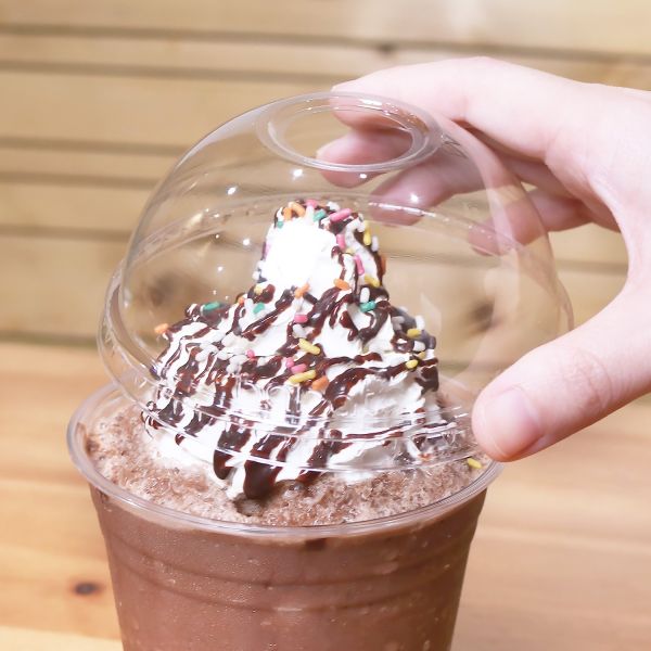 Clear Karat 98mm PET Plastic Dome Lids on matching cup with chocolate frozen drink