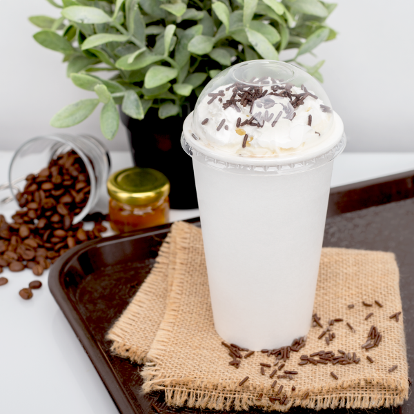 Clear Karat 90mm PET Plastic Dome Lids on paper cup with iced coffee and whip cream inside