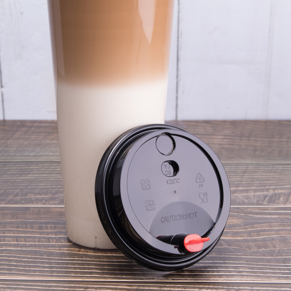 Black Karat 90mm Sipper Dome Lid for 16/24 oz Tall Premium PP Plastic Cup next to matching cup with a latte