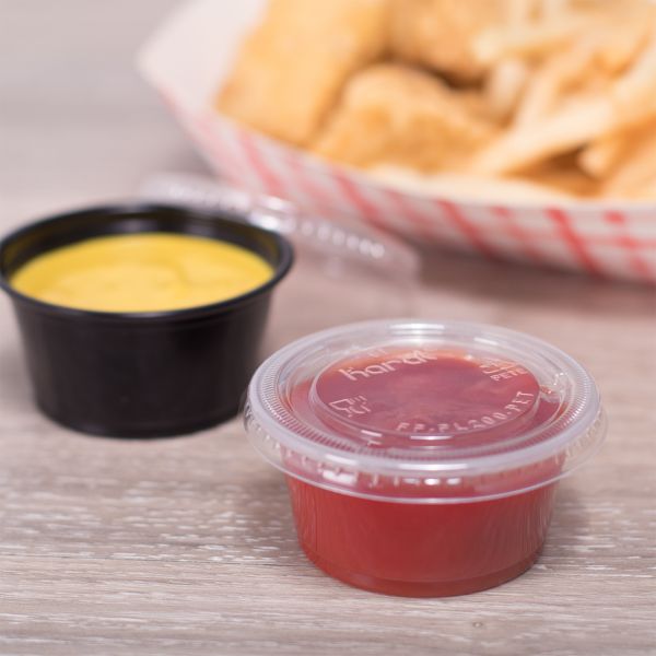 Clear Karat 1oz Squat-2oz PET Plastic Portion Cup Lid on clear cup filled with ketchup