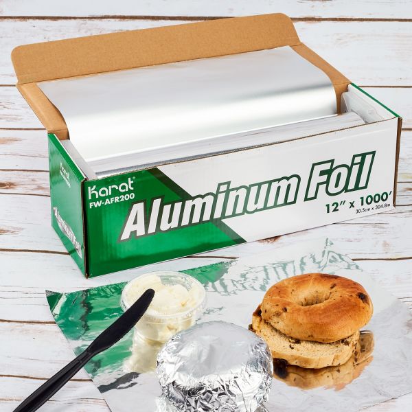 Karat 12"x 1000" Standard Aluminum Foil Roll being used to wrap a bagel