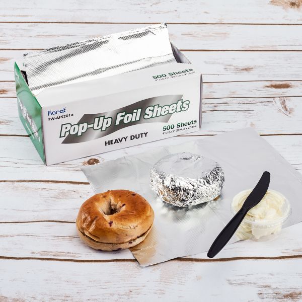 Karat 9" x 10.75" Heavy-Duty Pop-up Aluminum Foil Sheets being used to wrap bagel