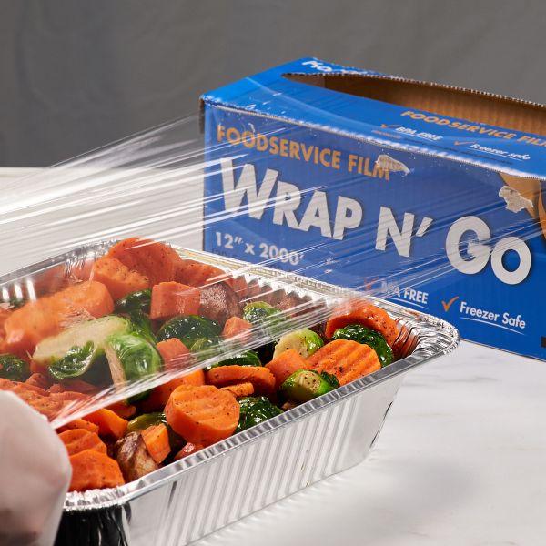 Karat 12" x 2000' WRAP N'GO Foodservice Film with Serrated Cutter being used to cover vegetables